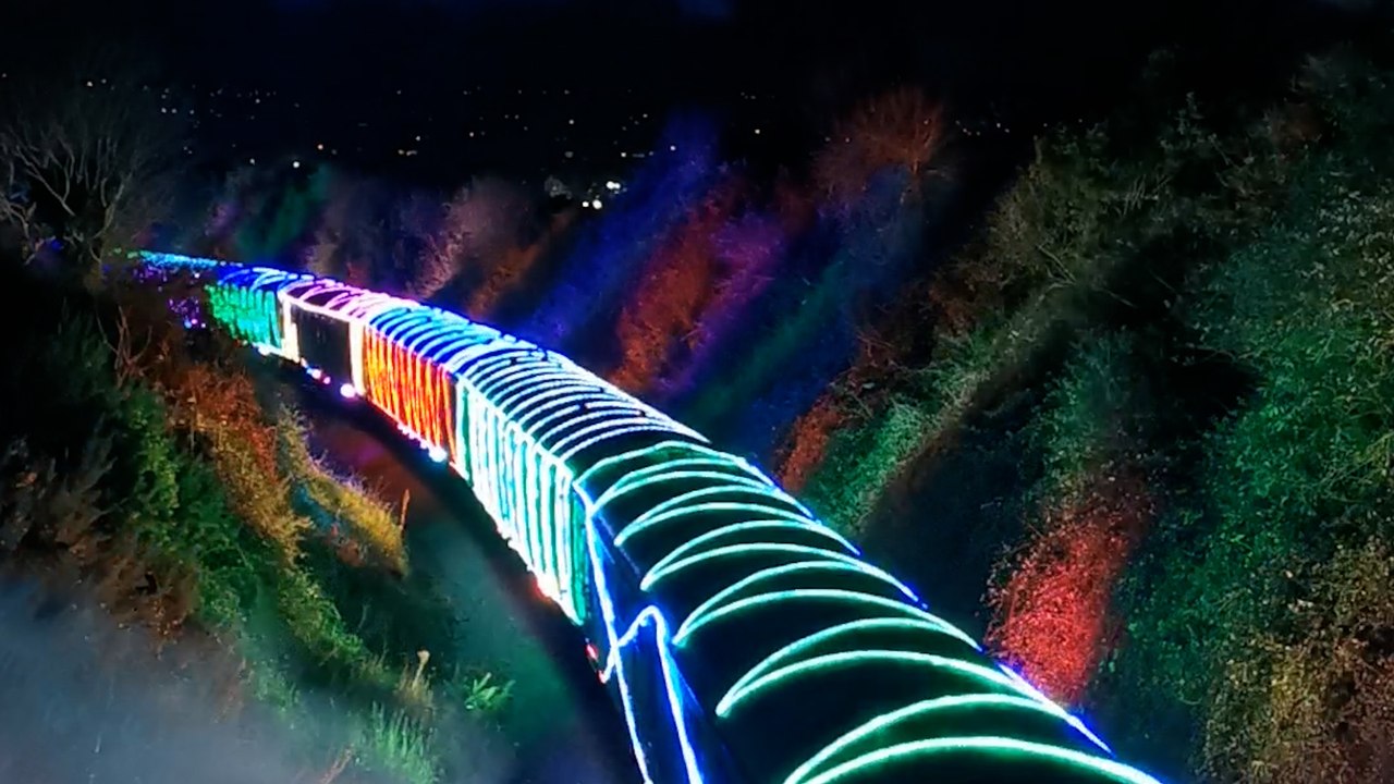 Schillerndes Filmmaterial zeigt einen mit Weihnachtslichtern erleuchteten Zug