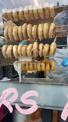Donuts being glazed in the window of a donut shop!