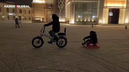 Kars'ta baba ile oğlunun elektrikli bisikletle kızak keyfi