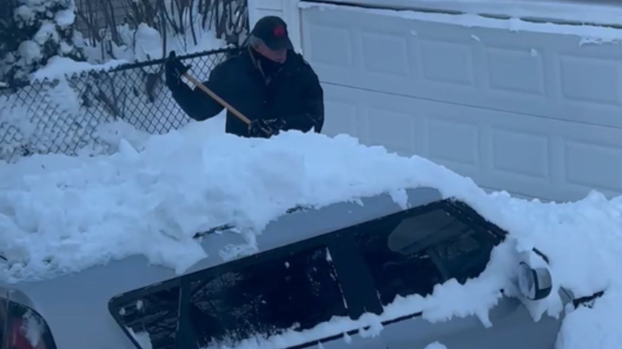 Determined man clears snow from his car after a snowstorm in Buffalo, New York
