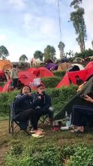 Menikmati minuman hangat saat camping pagi hari