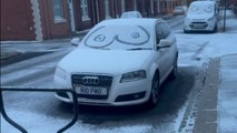 Eye doodles on snow-covered windscreens of cars as winter sets in