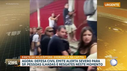 Chuvas alagam estação de metrô em São Paulo, e pessoas se seguram em grade para não serem arrastadas