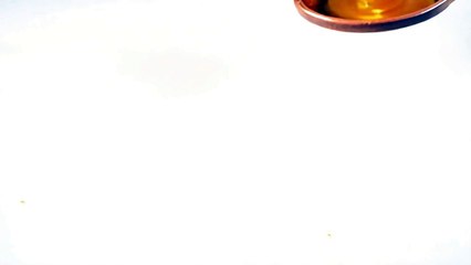 Video of a wooden spoon pouring honey onto a white surface, creating a golden, viscous pool. The honey flows smoothly, creating a satisfying sound and visual effect.