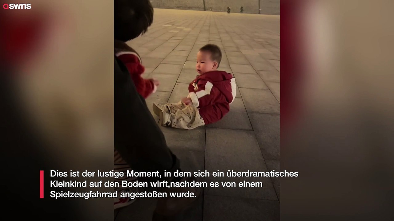 Überdramatisches Kleinkind wirft sich auf den Boden, nachdem es von einem Spielzeugfahrrad angestupst wurde