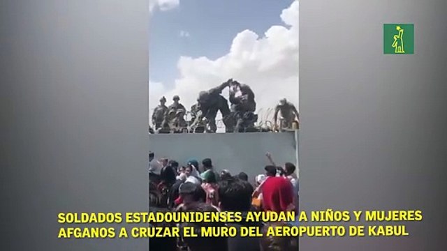 soldados estadounidenses ayudan a niños y mujeres afganos a cruzar el muro del aeropuerto de Kabul