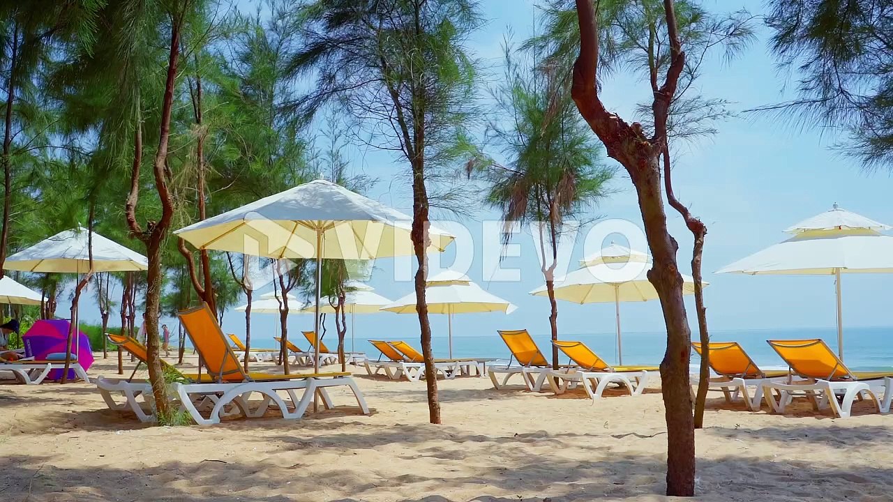Natural sand tropical beach and sea wave with yellow beach bench under white parasol umbrella and trees on tropical island beach