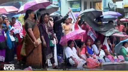 മഴയില്‍ കുതിര്‍ന്ന് ആശമാരുടെ സമരം, റോഡില്‍ കുത്തിയിരുന്ന് മഴയത്തും ആശമാരുടെ സമരം