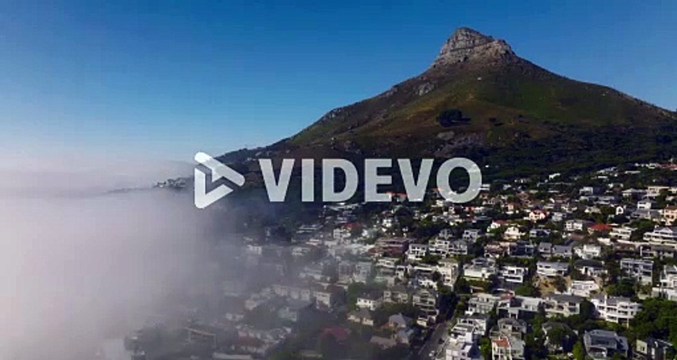 Aerial view of Camps Bay luxurious residential suburb and steep slope with rocky peak above