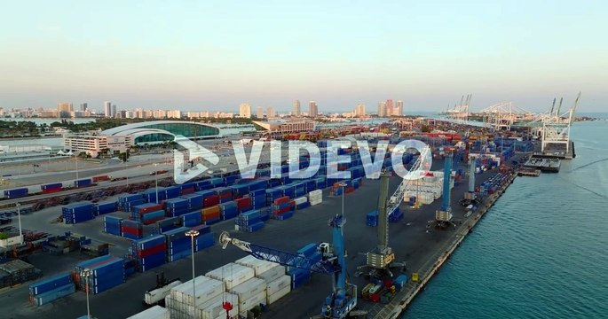 Rising shot of containers and cranes in harbour at twilight