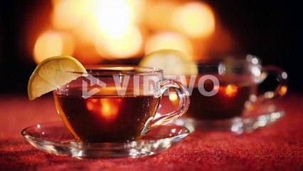 Two Cups With Tea And Lemon On The Background Of The Fireplace Where The Fire Burns
