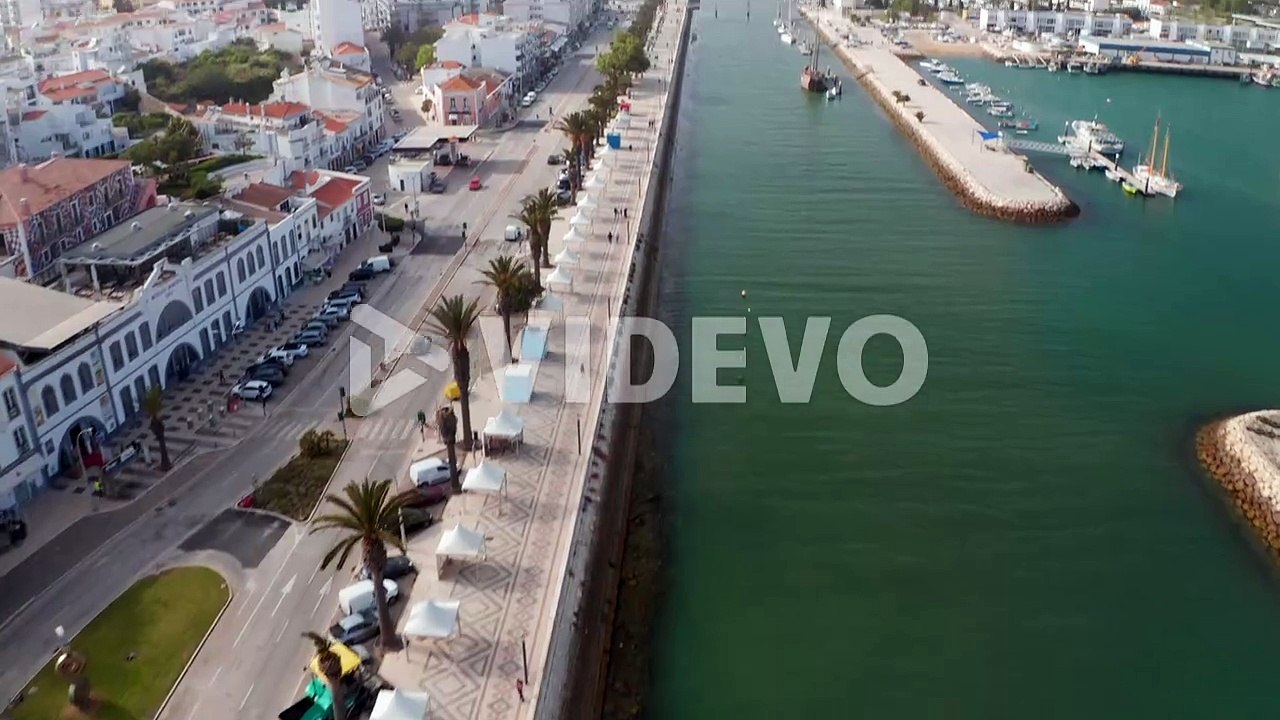 Aerial drone view of picturesque city of Lagos Algarve, Portugal, drone flying forward above harbor canal, day