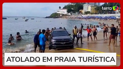 Carro fica atolado e parcialmente submerso na praia do Porto da Barra em Salvador