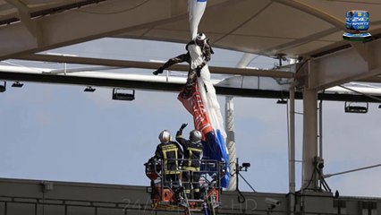 A PARACHUTIST crashed into the roof of a stadium and had to cling on for dear life in terrifying scenes