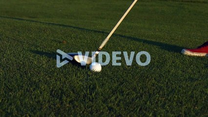 A golfer lining up a shot with a ball on a golf course