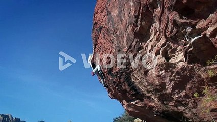 A woman climbs the side of a mountain