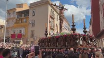 Un hombre echa un cubo de agua a un Cristo en una procesión en Málaga