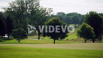 Yellow golf flag waving in the wind on a golf course surrounded by trees
