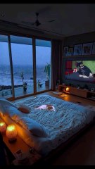 Elegant Ocean View Bedroom with Glass Wall, Cozy Bed, Soft Lights, Cat Resting, Evening Clouds, and Tom and Jerry on TV.#reel#reelinstagram#reelfacebook#fyp#foryou#luxurybedroomretreat#cozyhaven#softlightingbliss#follow