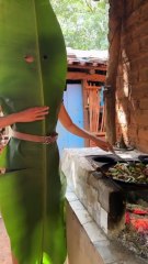 Brazilian woman wears big leaf to protect herself while cooking
