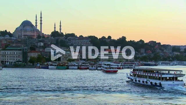 Boats pass in the harbor in front of the mosques of Istanbul Turkey at dusk