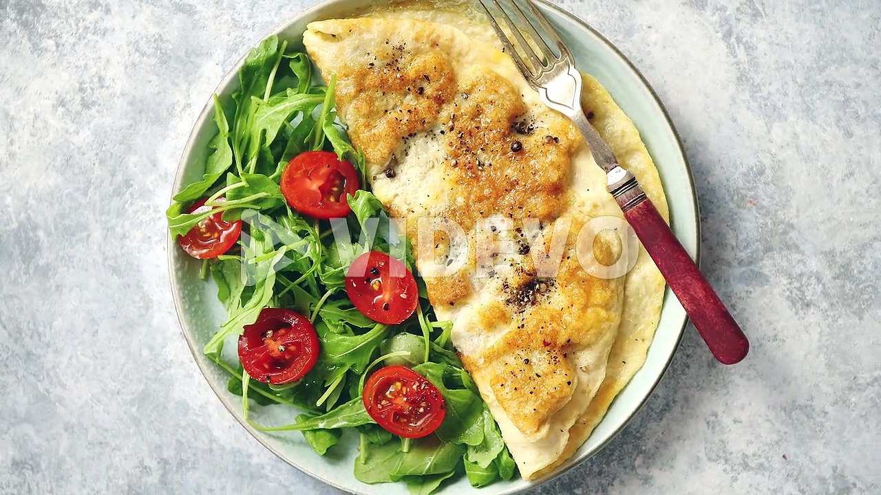 Classic egg omelette served with cherry tomato and arugula salad on side