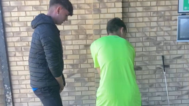 Lad tries to swing a golf ball through his mate’s legs but fails