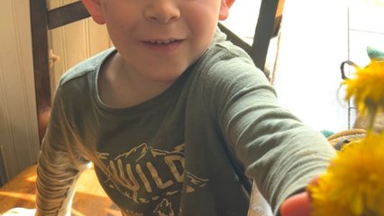 4 y/o boy waits patiently to surprise his mother with dandelion flowers