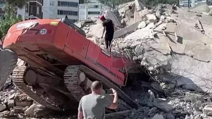 Ağır hasarlı bina yıkılırken iş makinesinin üzerine devrildi