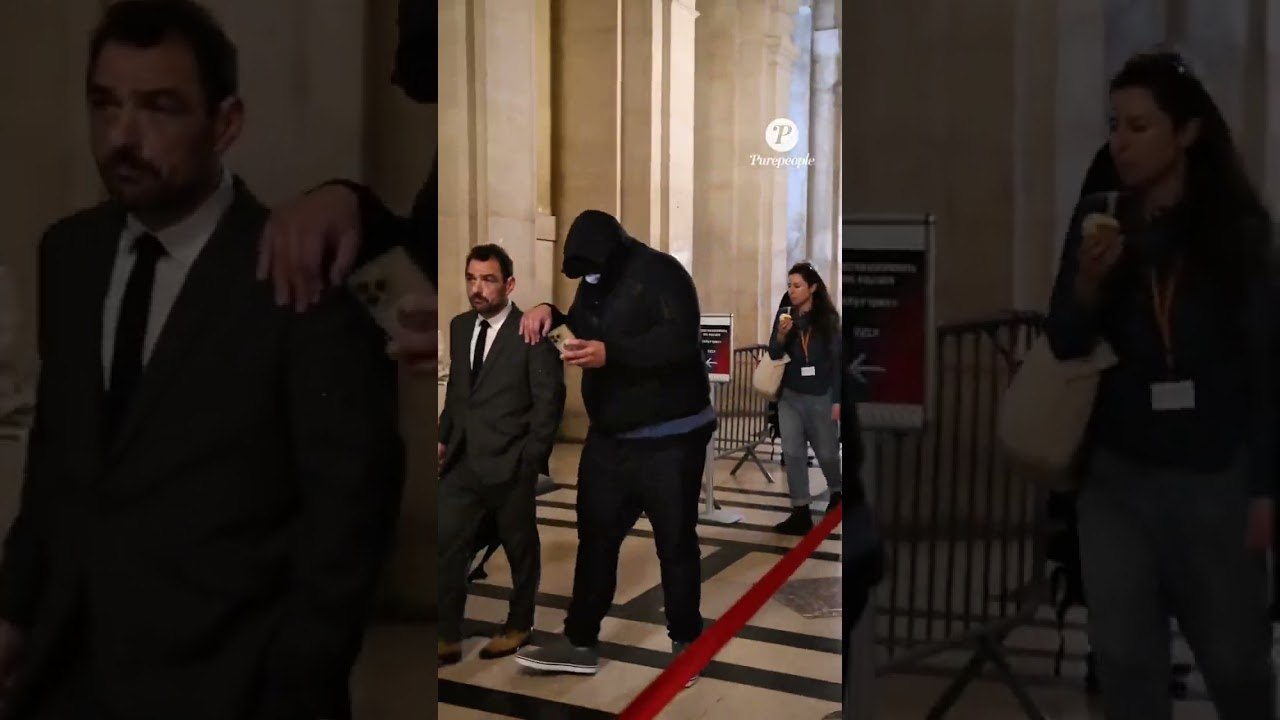 L’un des accusé quitte le tribunal caché derrière un masque et une capuche