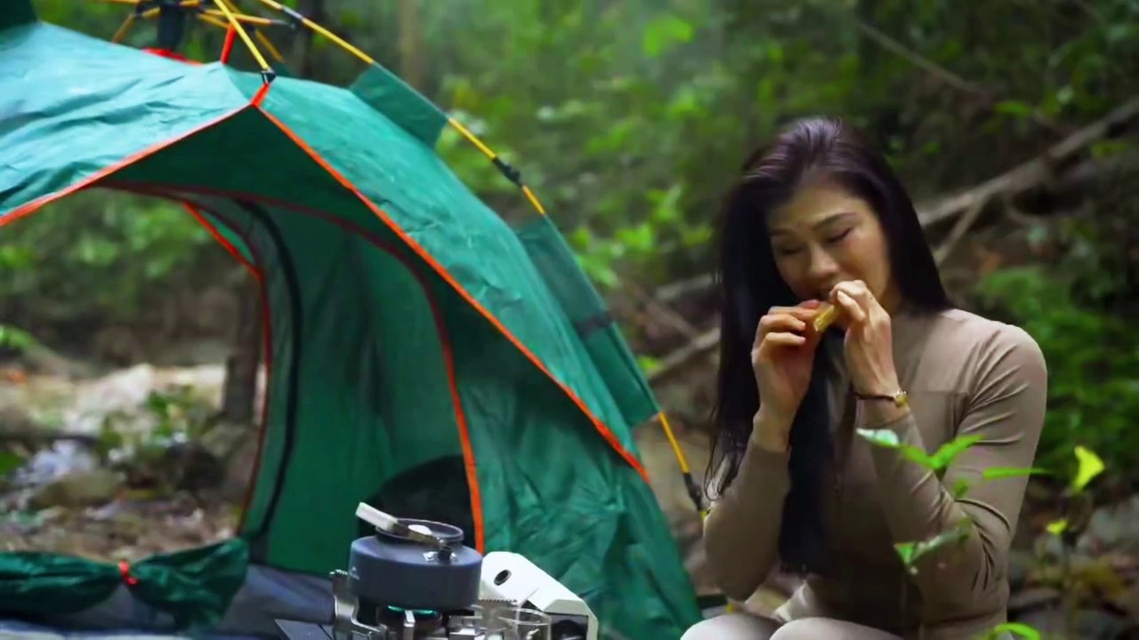 Solo girl camping alone in the woods and cooking by the stream