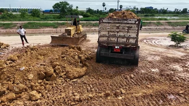 5T truck carrying soil to fill large lakes and flooded areas with a small dozer