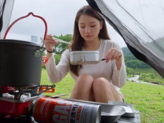 Solo girl camping by the river on a rainy day