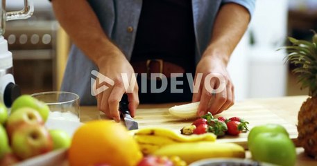 a young man slicing bananas in the kitchen at home