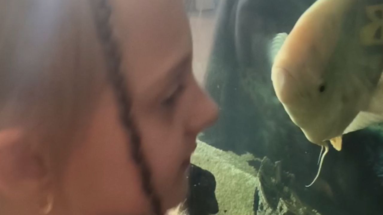 Playful kids imitate a fish that looks like it’s yelling in aquarium