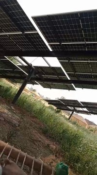 solar panel installation on our tubewell system. Two sturdy poles were self-installed to support the panels, and the setup is shown enduring strong wind conditions. real rural environment. self-reliance and clean energy utilization in farming areas.