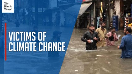 Pakistanis wade through waist-deep floodwater in Lahore after heavy rain