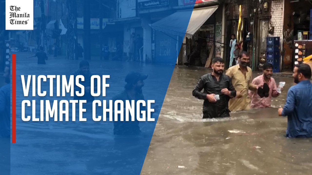Pakistanis wade through waist-deep floodwater in Lahore after heavy rain