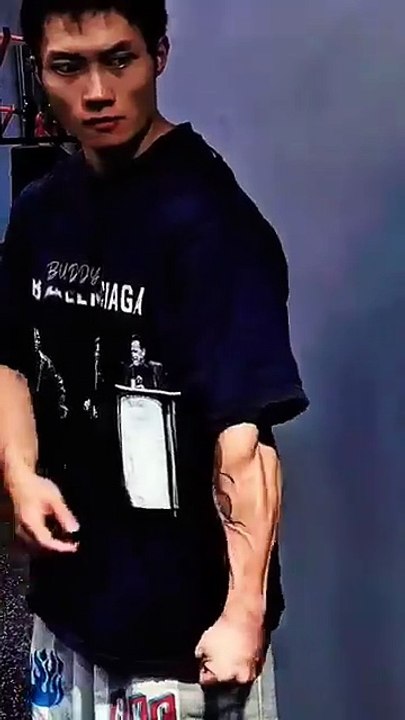 A young man displays his arm muscles and abs after completing a workout.