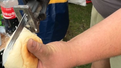 Gentleman uses power tool to cut a burger bun at no-utensil BBQ