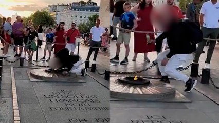 Un hombre se enciende un cigarro con la llama de la tumba del soldado desconocido en París