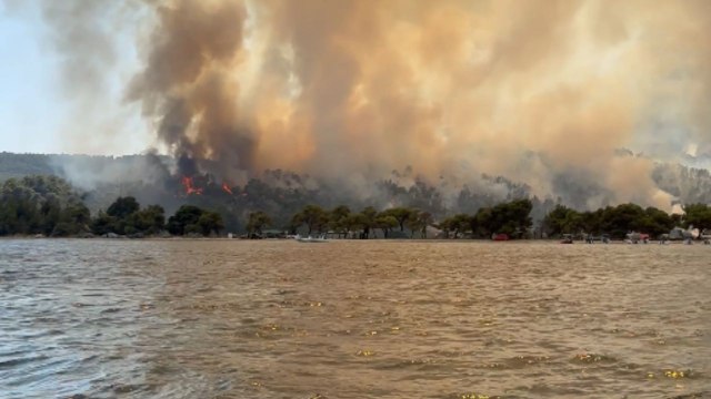 Firefighting helicopter battles raging wildfire in Greek seaside village of Vourvourou