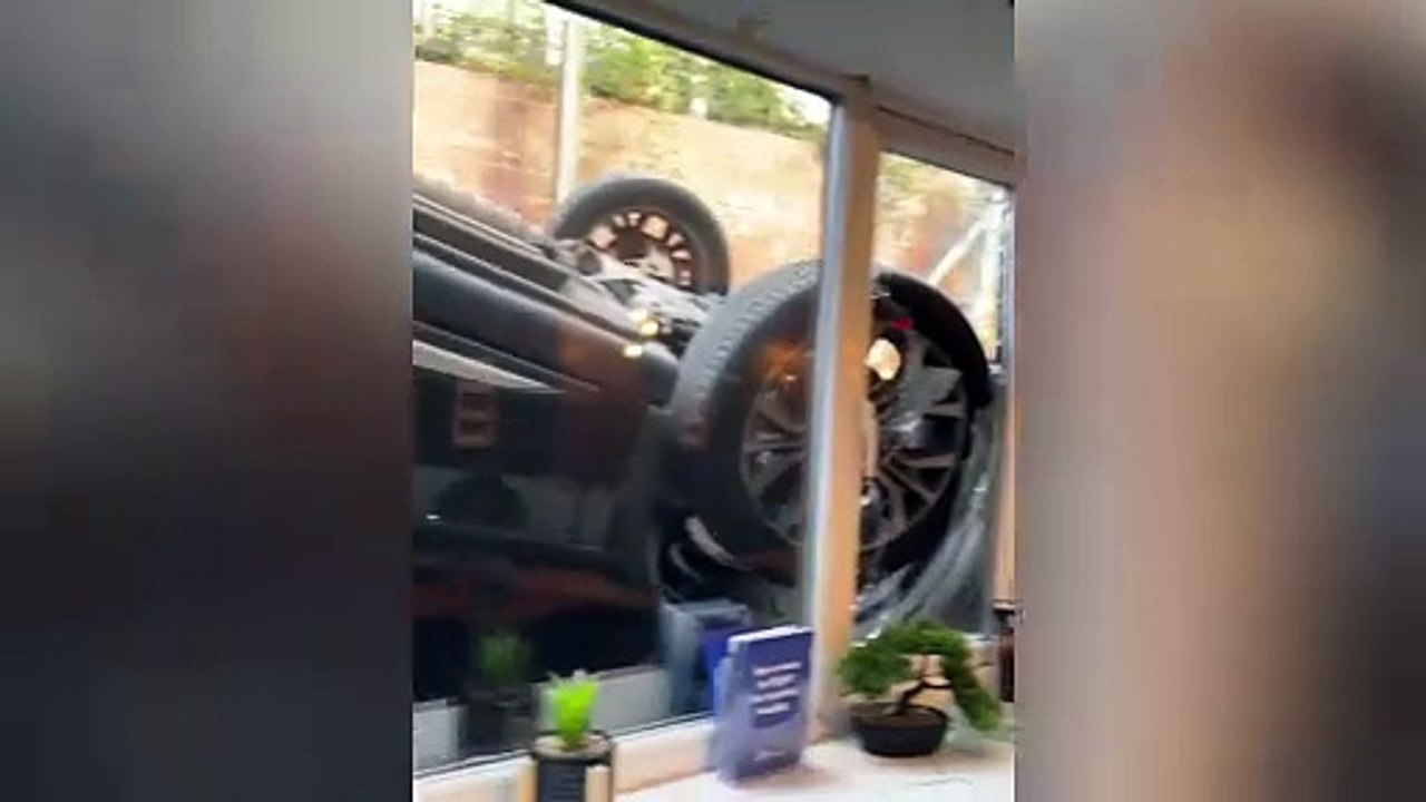 Shocking video shows the scene after a runaway car fell off a hill, flipped upside down, and crashed in to the window of a gym