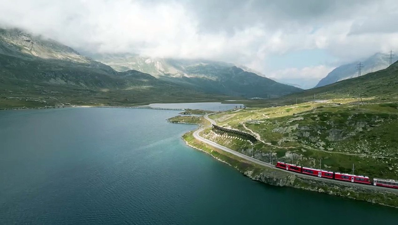 A Train Traveling Through a Mountain Valley Next to a Lake