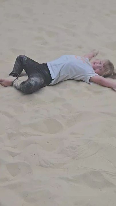 Jasmine and Joseph playing in the sand doing sand angels