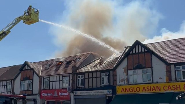 Crowd watches firefighters in action after fire destroyed a building in Kingsbury