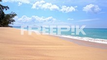 foamy waves rolling towards empty island white sand beach and emerald tranquil sea tides, cloudy sky, vacation template, copy space minimalistic