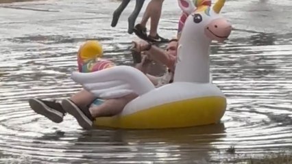 Rain drenches Parookaville but inflatable unicorn tube keeps a boy entertained