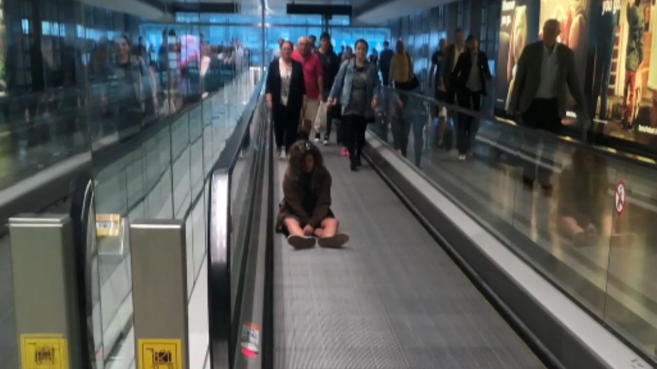 Woman's idea to sit on moving walkway at airport results in comical panic