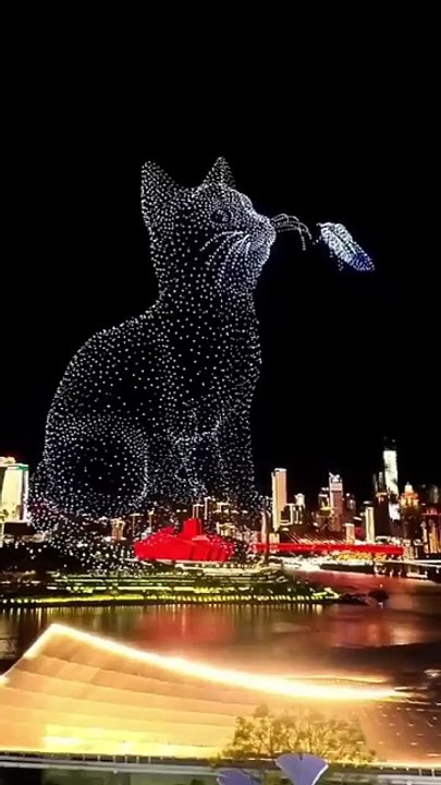 The drones moved together to create glowing shapes like a giant running kid and swirling clouds above tall buildings.